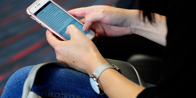 DALLAS, TX - SEPTEMBER 21, 2017: A woman uses her smartphone while waiting to board a plane at the Dallas/Fort Worth International Airport.